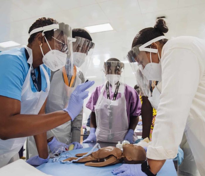 Loveline Ndashi, Safe Surgery Project Facilitator, in the GLM Simulation Lab, with MCB Neonatal Resuscitation course participants, during a scenario training.