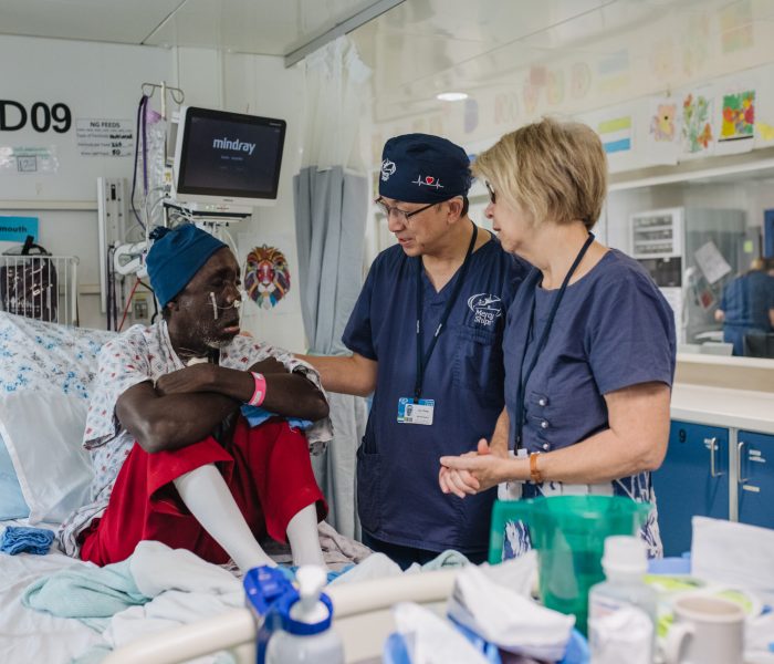 Leo Cheng, Max Fax Surgeon, Hilary Cheng, Hospital Chaplain, with patient on ward.