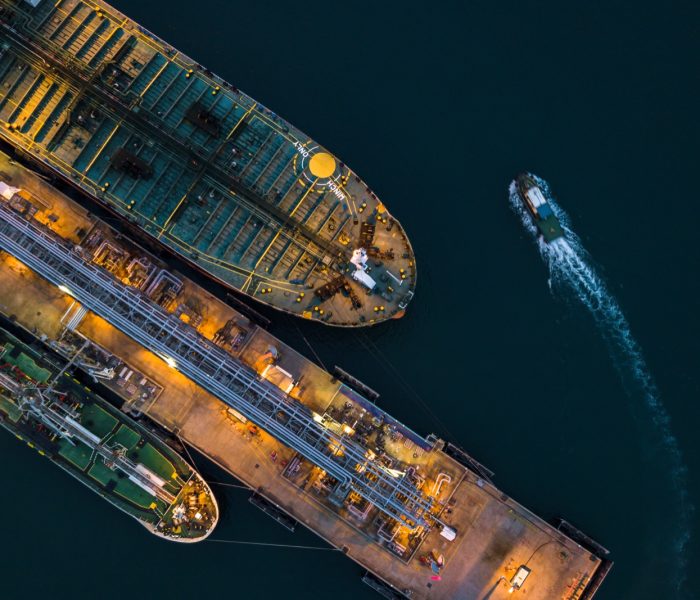 Aerial view tanker ship vessel unloading at port at night, Global business logistic import export oil and gas petrochemical with tanker ship transportation oil from dock refinery.